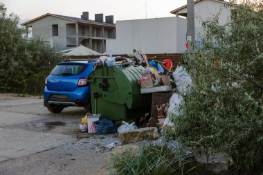 Çöp konteyneri, çöp ile kalabalık. Yolda terkedilmiş katı ev çöp. Çevre kirliliği. Ekolojik sorun. Terk edilmiş çöp yolda. Büyük bir şehirde atık yönetimi sorunu