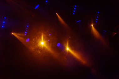 Stage lights. Several projectors in dark. A bright colored spotlight permeates the darkness. Light from the stage, rock concert. Lighting equipment. Several projectors on theatrical lighting system clipart
