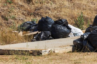 Büyük siyah plastik çöp torbaları çöp yığını Şehir Parkı ekoloji takunya. Büyük bir şehir, endüstriyel ve yerel atık kullanımı ekolojik sorunu. Çöp poşetleri