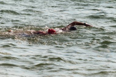 Yüzücü denizde yüzüyor. Atlet triatlet yüzücü sudan boşalmasına neden olur. Triathletes trenler bir Ironman için profesyonel bir atlet. Sporcu güzel yarışmalarda mavi deniz suda yüzer.