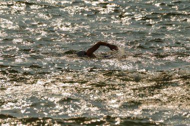 Yüzücü denizde yüzüyor. Atlet triatlet yüzücü sudan boşalmasına neden olur. Triathletes trenler bir Ironman için profesyonel bir atlet. Sporcu güzel yarışmalarda mavi deniz suda yüzer.