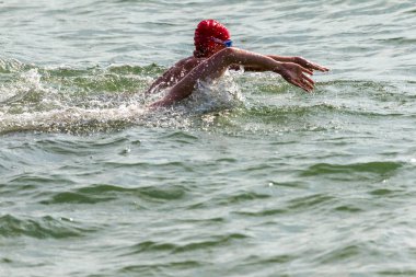Yüzücü denizde yüzüyor. Atlet triatlet yüzücü sudan boşalmasına neden olur. Triathletes trenler bir Ironman için profesyonel bir atlet. Sporcu güzel yarışmalarda mavi deniz suda yüzer.