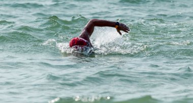 Yüzücü denizde yüzüyor. Atlet triatlet yüzücü sudan boşalmasına neden olur. Triathletes trenler bir Ironman için profesyonel bir atlet. Sporcu güzel yarışmalarda mavi deniz suda yüzer.