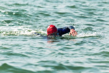 Yüzücü denizde yüzüyor. Atlet triatlet yüzücü sudan boşalmasına neden olur. Triathletes trenler bir Ironman için profesyonel bir atlet. Sporcu güzel yarışmalarda mavi deniz suda yüzer.