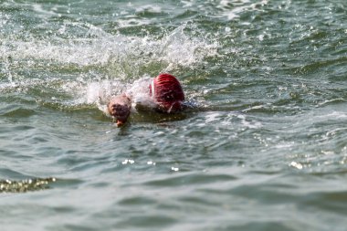 Yüzücü denizde yüzüyor. Atlet triatlet yüzücü sudan boşalmasına neden olur. Triathletes trenler bir Ironman için profesyonel bir atlet. Sporcu güzel yarışmalarda mavi deniz suda yüzer.