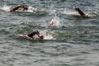 Yüzücü denizde yüzüyor. Atlet triatlet yüzücü sudan boşalmasına neden olur. Triathletes trenler bir Ironman için profesyonel bir atlet. Sporcu güzel yarışmalarda mavi deniz suda yüzer.