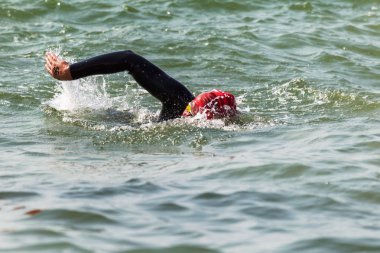 Yüzücü denizde yüzüyor. Atlet triatlet yüzücü sudan boşalmasına neden olur. Triathletes trenler bir Ironman için profesyonel bir atlet. Sporcu güzel yarışmalarda mavi deniz suda yüzer.