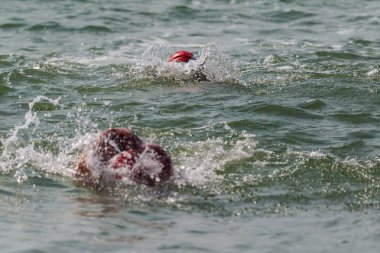 Yüzücü denizde yüzüyor. Atlet triatlet yüzücü sudan boşalmasına neden olur. Triathletes trenler bir Ironman için profesyonel bir atlet. Sporcu güzel yarışmalarda mavi deniz suda yüzer.