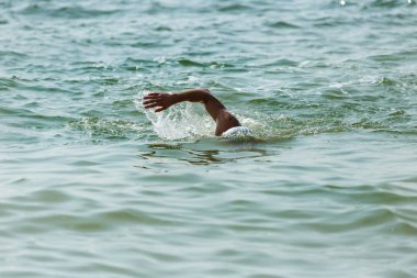 Yüzücü denizde yüzüyor. Atlet triatlet yüzücü sudan boşalmasına neden olur. Triathletes trenler bir Ironman için profesyonel bir atlet. Sporcu güzel yarışmalarda mavi deniz suda yüzer.
