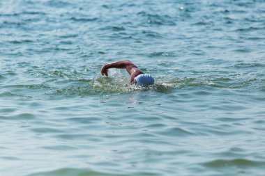Yüzücü denizde yüzüyor. Atlet triatlet yüzücü sudan boşalmasına neden olur. Triathletes trenler bir Ironman için profesyonel bir atlet. Sporcu güzel yarışmalarda mavi deniz suda yüzer.