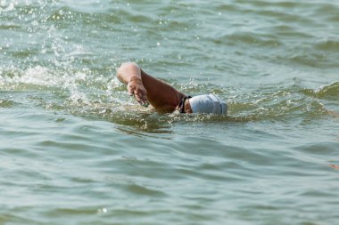 Yüzücü denizde yüzüyor. Atlet triatlet yüzücü sudan boşalmasına neden olur. Triathletes trenler bir Ironman için profesyonel bir atlet. Sporcu güzel yarışmalarda mavi deniz suda yüzer.