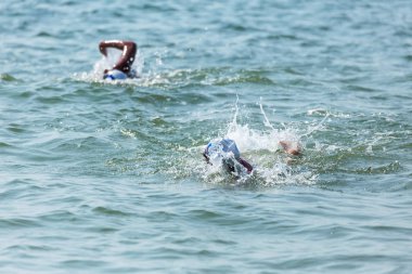 Yüzücü denizde yüzüyor. Atlet triatlet yüzücü sudan boşalmasına neden olur. Triathletes trenler bir Ironman için profesyonel bir atlet. Sporcu güzel yarışmalarda mavi deniz suda yüzer.