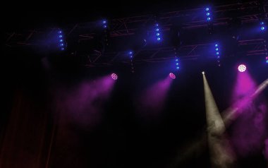 Sahne ışıkları. Bazı projektörler karanlıkta. Parlak renkli sahne ışığı karanlığı nüfuz eder. Işık aşamasından, rock konseri. Aydınlatma donanımları. Tiyatro aydınlatma sistemi üzerinde çeşitli projektörler