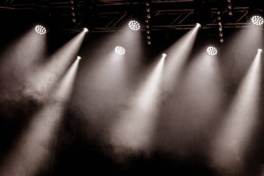 Stage lights. Several projectors in dark. A bright colored spotlight permeates the darkness. Light from the stage, rock concert. Lighting equipment. Several projectors on theatrical lighting system clipart