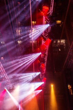 Sahne ışıkları. Bazı projektörler karanlıkta. Parlak renkli sahne ışığı karanlığı nüfuz eder. Işık aşamasından, rock konseri. Aydınlatma donanımları. Tiyatro aydınlatma sistemi üzerinde çeşitli projektörler