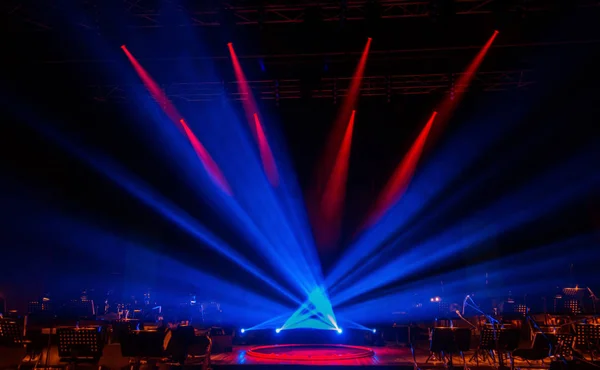 Stage lights. Several projectors in dark. A bright colored spotlight permeates the darkness. Light from the stage, rock concert. Lighting equipment. Several projectors on theatrical lighting system