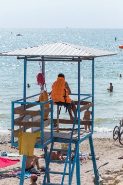 Cankurtaran üzerinde gözetleme kulesi sahilde denizin yıkananlara ilgilenir. Turuncu bir hayat şamandıra ile kurtarıcı gözlem kulesi, denizin önünde oturur.