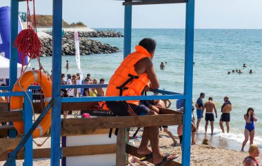 Odessa, Ukrayna - 19 Ağustos 2018: Sahilde bir kule üzerinde bir cankurtaran deniz yıkananlara dışarı bakar. Kurtarıcı turuncu bir hayat şamandıra ile gözlem kulesi, denizin önünde oturur