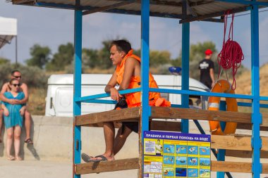 Odessa, Ukrayna - 19 Ağustos 2018: Sahilde bir kule üzerinde bir cankurtaran deniz yıkananlara dışarı bakar. Kurtarıcı turuncu bir hayat şamandıra ile gözlem kulesi, denizin önünde oturur