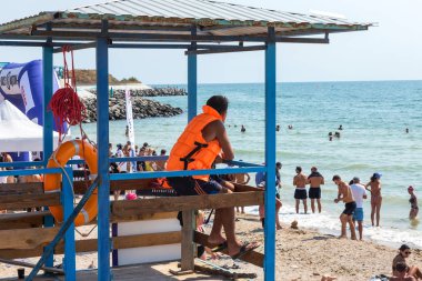 Odessa, Ukrayna - 19 Ağustos 2018: Sahilde bir kule üzerinde bir cankurtaran deniz yıkananlara dışarı bakar. Kurtarıcı turuncu bir hayat şamandıra ile gözlem kulesi, denizin önünde oturur