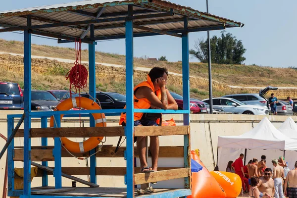 Odessa, Ukrayna - 19 Ağustos 2018: Sahilde bir kule üzerinde bir cankurtaran deniz yıkananlara dışarı bakar. Kurtarıcı turuncu bir hayat şamandıra ile gözlem kulesi, denizin önünde oturur