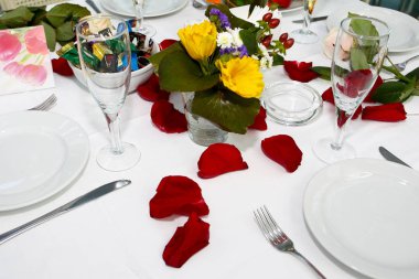 Yemek, şarap gözlük, masada çatal bıçak takımı. Tableclot, kırmızı gül yaprakları rastgele dağılmış. Festival masa dekorasyonu Sevgililer Günü'nde, düğün hizmet. Menü için arka plan olarak. Tablo ayarı