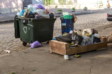 Çöp çöp torbası dolu çöp tenekeleri şehir sokak ile yığını. Birçok ev atık plastik torba evin önünde. Dökümü, plastik atıkların çevre kirliliğinin