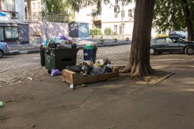 Çöp çöp torbası dolu çöp tenekeleri şehir sokak ile yığını. Birçok ev atık plastik torba evin önünde. Dökümü, plastik atıkların çevre kirliliğinin