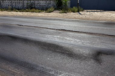 Bozuk yol çukurların ve nokta ile kıyılmış asfalt zarar görmüş. Çok kötü asfalt yol ile büyük trenche. Korkunç teknoloji yol asfalt üretim. Yumuşak asfalt ısı erir