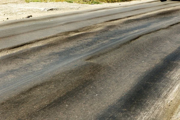 Bozuk yol çukurların ve nokta ile kıyılmış asfalt zarar görmüş. Çok kötü asfalt yol ile büyük trenche. Korkunç teknoloji yol asfalt üretim. Yumuşak asfalt ısı erir