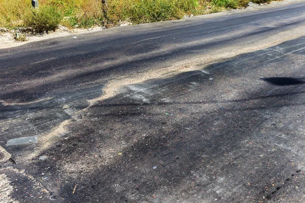 Bozuk yol çukurların ve nokta ile kıyılmış asfalt zarar görmüş. Çok kötü asfalt yol ile büyük trenche. Korkunç teknoloji yol asfalt üretim. Yumuşak asfalt ısı erir