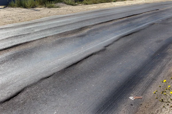Bozuk yol çukurların ve nokta ile kıyılmış asfalt zarar görmüş. Çok kötü asfalt yol ile büyük trenche. Korkunç teknoloji yol asfalt üretim. Yumuşak asfalt ısı erir