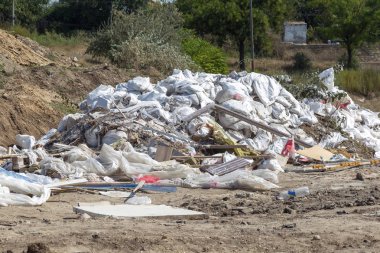 İnsanlar tarafından çevre kirliliği. Çorak içinde yasadışı çöp dökümü. Torbalarda bir çöplükte ev çöp yığını. Atık büyük bir yığın çöp Dağı'na uzanır