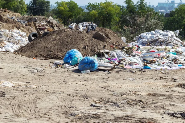 Pollution of the environment by people. Illegal garbage dump in the wasteland. A pile of household garbage in a dump in bags. A huge pile of waste extends to the garbage mountain