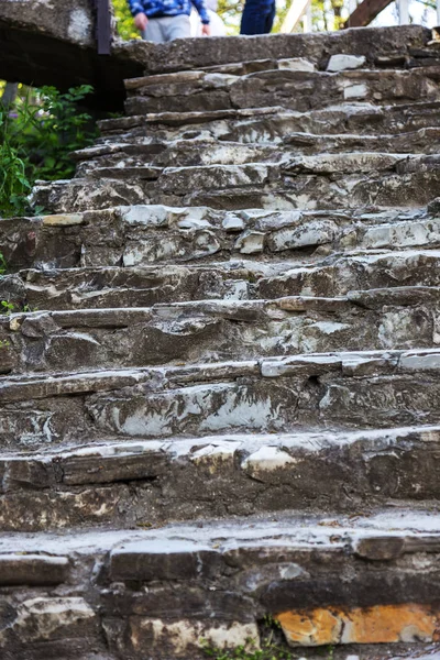 An old open outer stone staircase. Stone, cement steps of the old staircase with traces of weathering and destruction. An ancient stone staircase, ancient broken worn steps. Selective focus