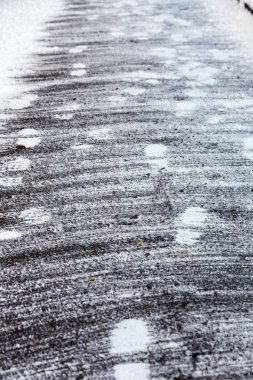 Kaldırım döşeme üzerinde kar izleri kar temizledi. Asfalt, ilk kar, şehir kar raylara. Ayak izi ayakkabı beton üzerinde şehir Kasım döşer. Yolda birçok ayak izleri var.