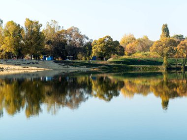 Otantik sonbahar manzara gölette Şehir Parkı. Sarı yapraklar yere ve suya düşer. Sıcak renkler ve patika ile renkli sonbahar manzaraları sayfaları ile kaplı. İnsanlar rahatlatıcı Park