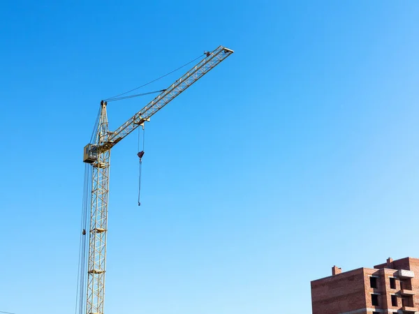 青空に対する建設中のレンガ高層ビルの近くのクレーン 近代的な建設 — ストック写真