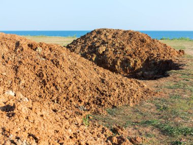 Kil ve kırmızı tehlike uyarı teypten yığını. Kil toprak ve su ile doldurun Hendek kazın.