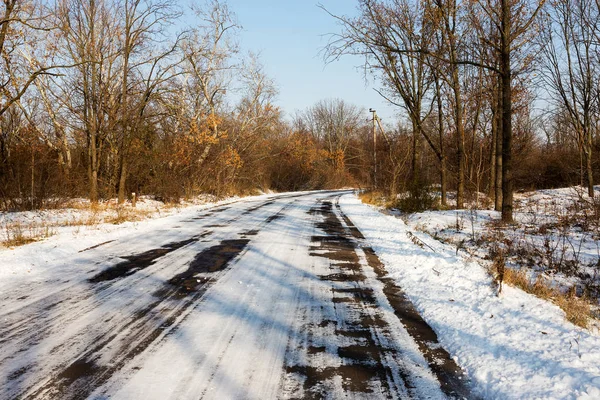 Karla kaplı asfalt yol karla kaplı ormanın içinden geçmektedir. Günbatımı kış orman içinde. Ormanıyla kaplı ağaçlar kar kış manzara. 