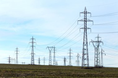 Yüksek gerilim hatları ve güneşli bir düz ve yeşil tarım peyzaj güç pilonlar mavi gökyüzünde cirrus bulutlar ile. Pilon ve iletim güç hattı 