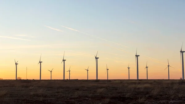 Wind Turbines at Dusk. Landscape sunset with windmills. Renewal source of electricity. Wind turbines field new technology for clean energy on mountain, sunset view with colorful twilight on sky