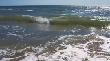 Kumsalda kumlu bir sahile vuran gelgit dalgalarıyla kumsal. Hava aracı videosu