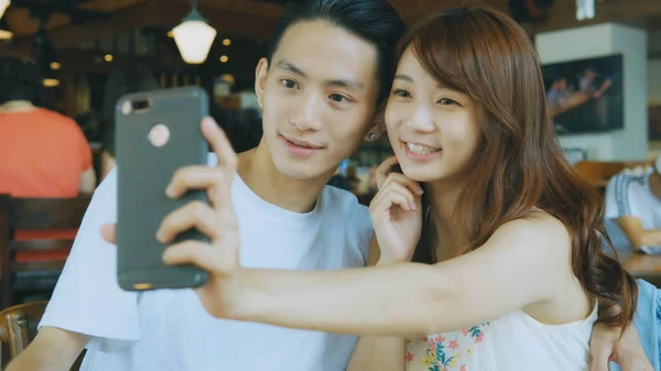 Asian couple using smart phone selfie