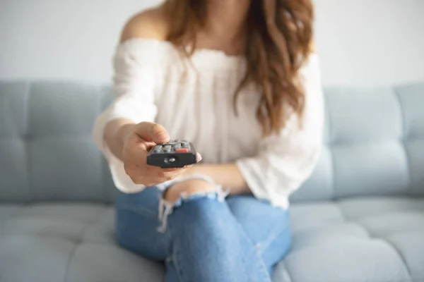 Asian woman using tv remote control on sofa