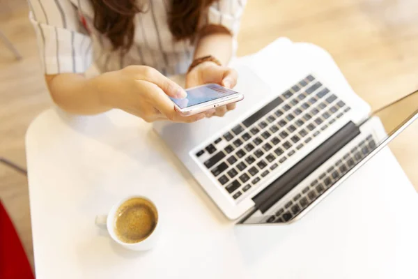 woman using smart phone and laptop in cafe.