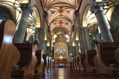 Bir katolik kilisesinin iç görünüşü bazı sütunları ve tavanı ahşap zeminin üstünde gösteriyor.