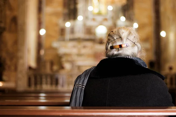 教会で祈る老婦人と背景にろうそくとボケ効果 — ストック写真