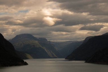 Aurlandsfjord 'u dağların arasında ve Norveç' te bulutlu bir gökyüzünün altında gösteren manzara