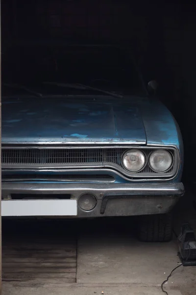 Ön tarafın yarısı eski Amerikan arabasının farlarıyla garajın karanlığında 1970 model Plymouth Belvedere.